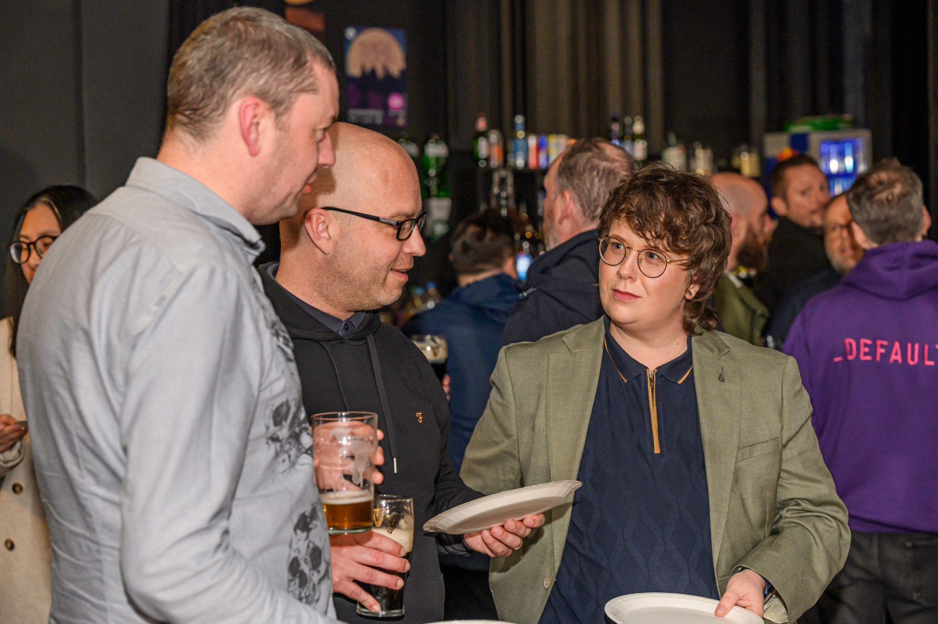 Three people chatting over drinks at a Belfast Tech Week social