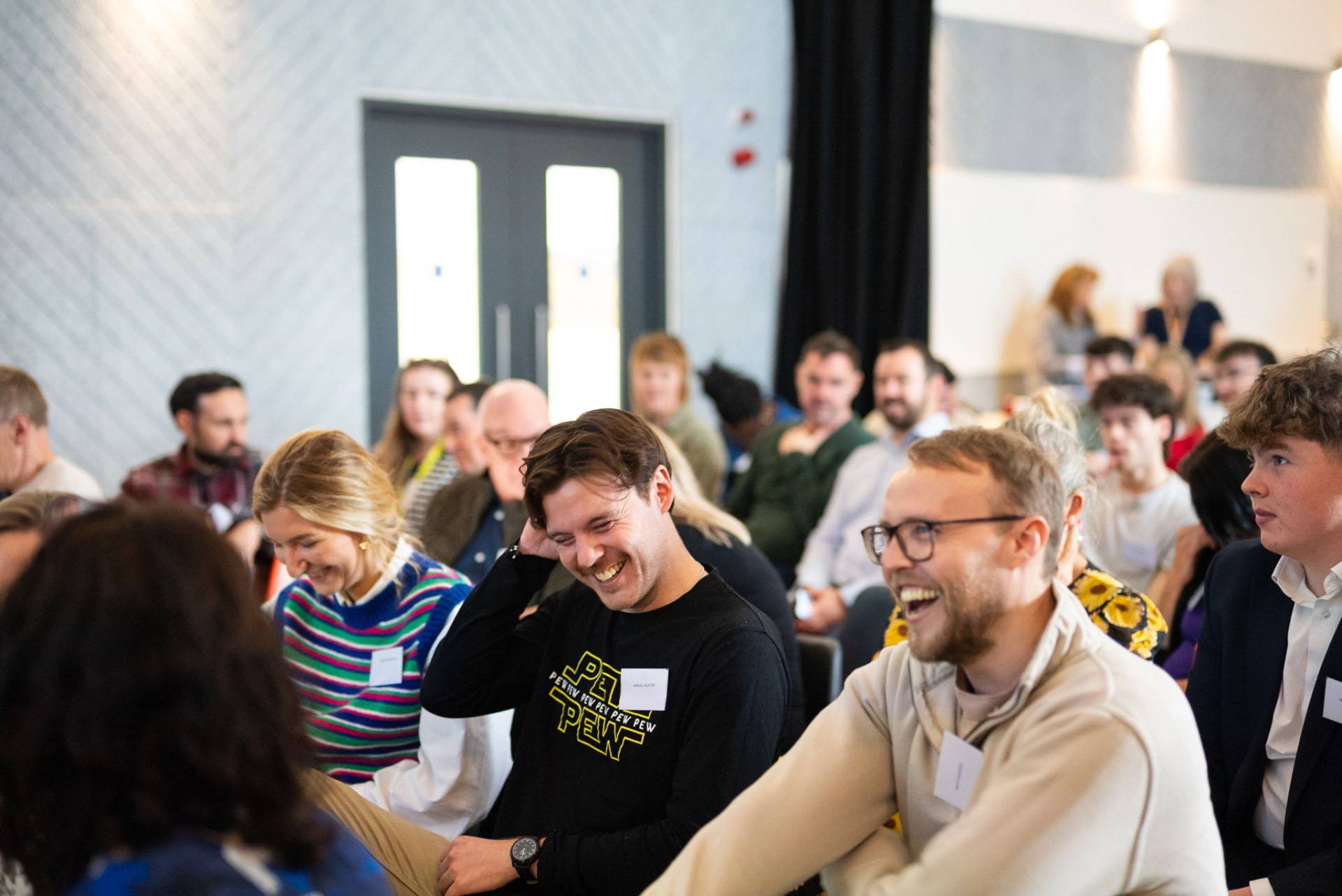 A laughing audience at a community tech event